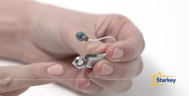 Picture of a Starkey hearing aid and a battery being inserted