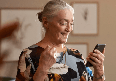 Picture of An elderly woman having a phone conversation and wearing Resound hearing aids