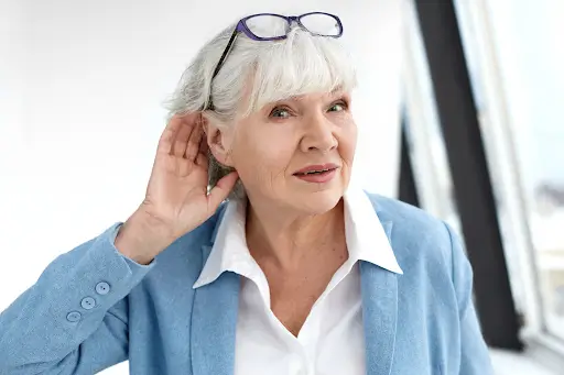 Woman holding her ear while listening, illustrating concern about a whooshing sound in the ear.